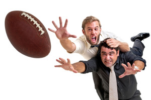 Businessmen playing rugby aka U.S. Football, isolated in white
